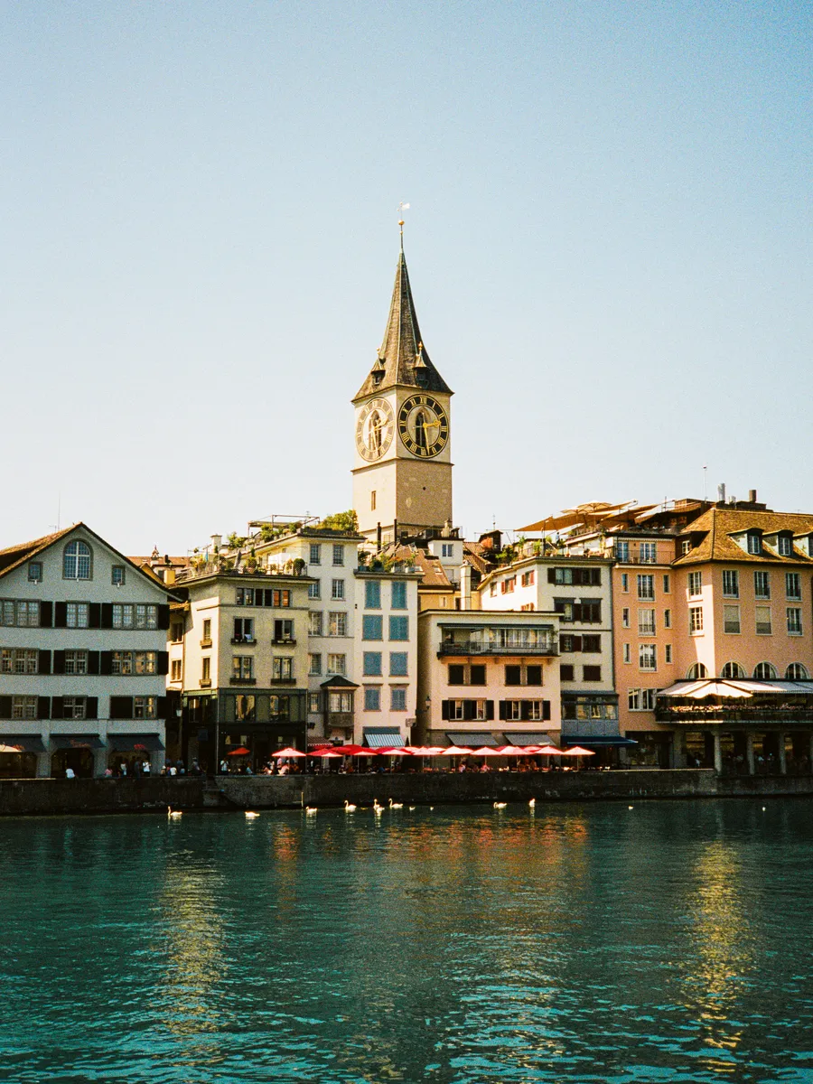 the clock tower of st. peter above the limmat riverfront, zürich